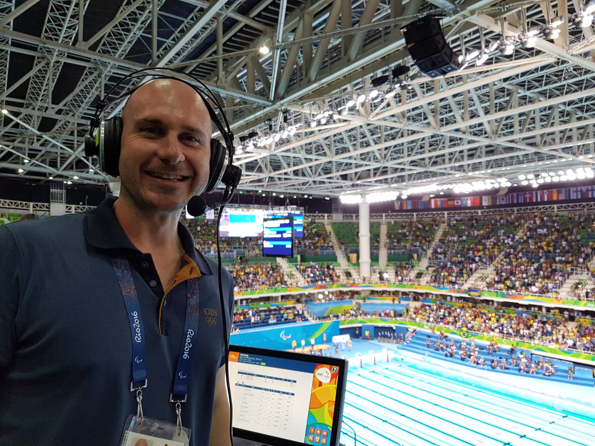 Dynamic Paralympic sports announcer at the Rio 2016 Olympics, showcasing professional broadcast equipment in a vibrant stadium setting.